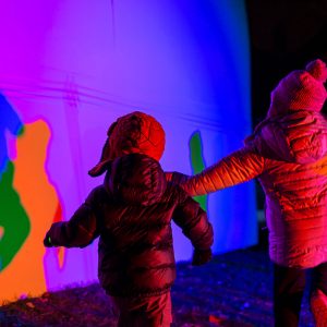 Kids dance in front of the brightly colored shadow play