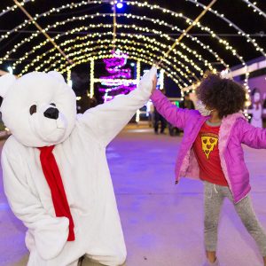 Polar bear high fives girl in a tunnel of lights.